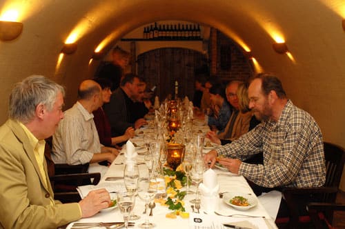 Festlich gedeckte lange Tafel mit Gästen im Gewölbekeller